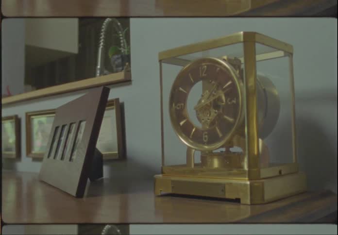An old table clock with yellow and gold colors with its hands stopped
