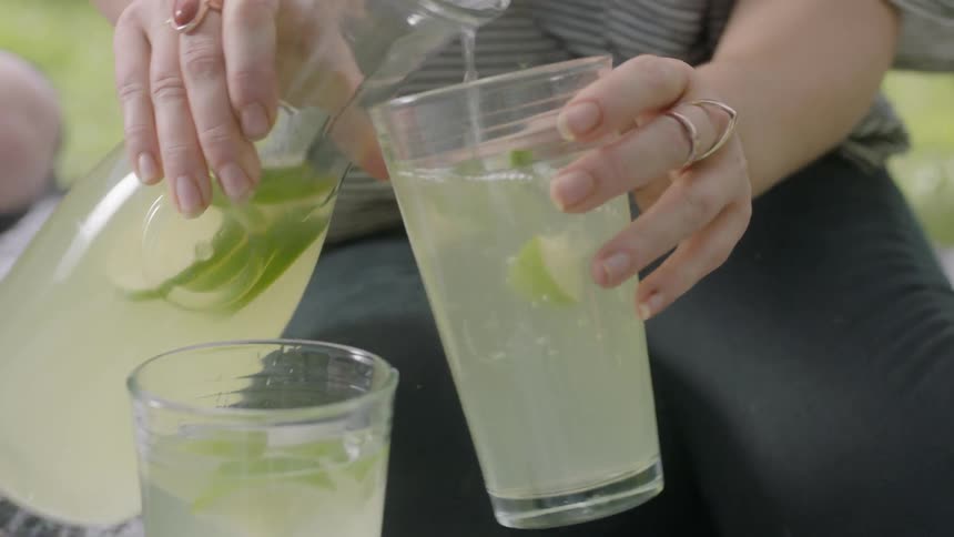 A woman pours lemonade into a glass