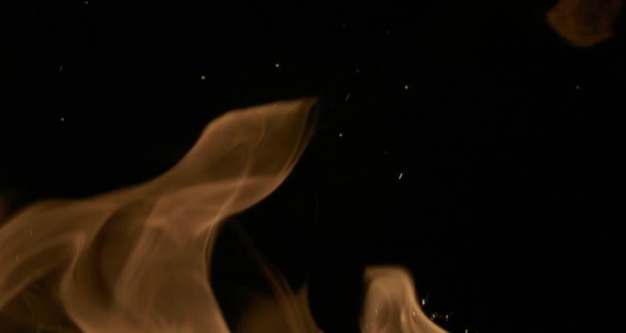 A flame rippling in the dark releasing sparks