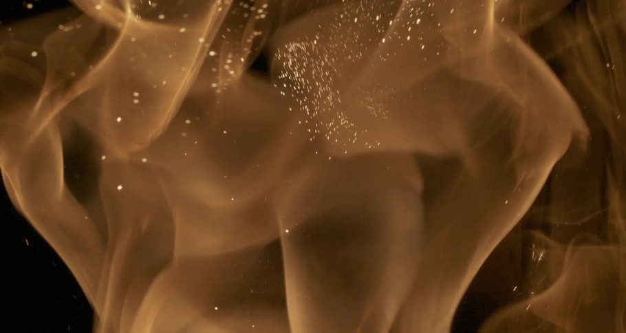 Glowing sparks and embers rise among orange flames as they float in the darkness