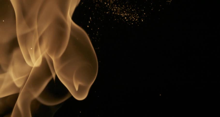 Orange flames rise through darkness creating sparks