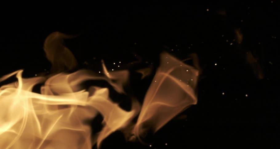 A flame rippling in the dark releasing sparks