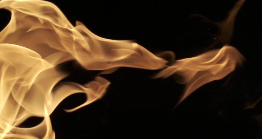 Glowing orange flames float as they rise in the darkness
