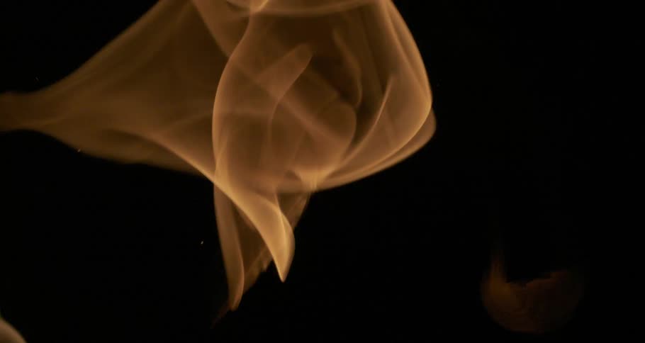 Glowing sparks and embers emerge from orange flames as they rise in the darkness