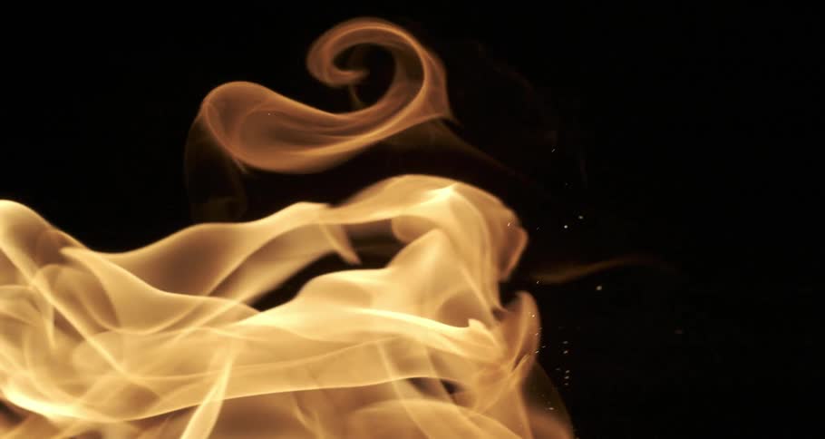 Glowing embers float among orange flames as they twist across the darkness