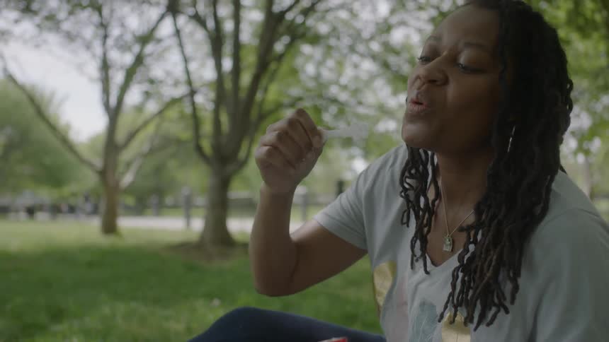 A woman is laughing and blowing bubbles