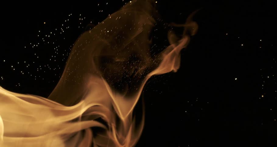 Glowing sparks and embers rise from orange flames as they twist and bend across the darkness