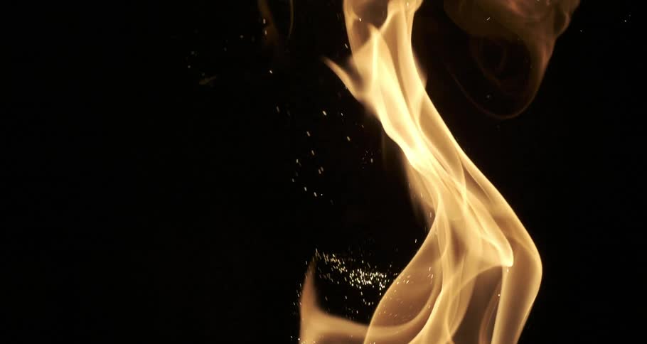 A blazing flame of fire with bright sparks on a black background
