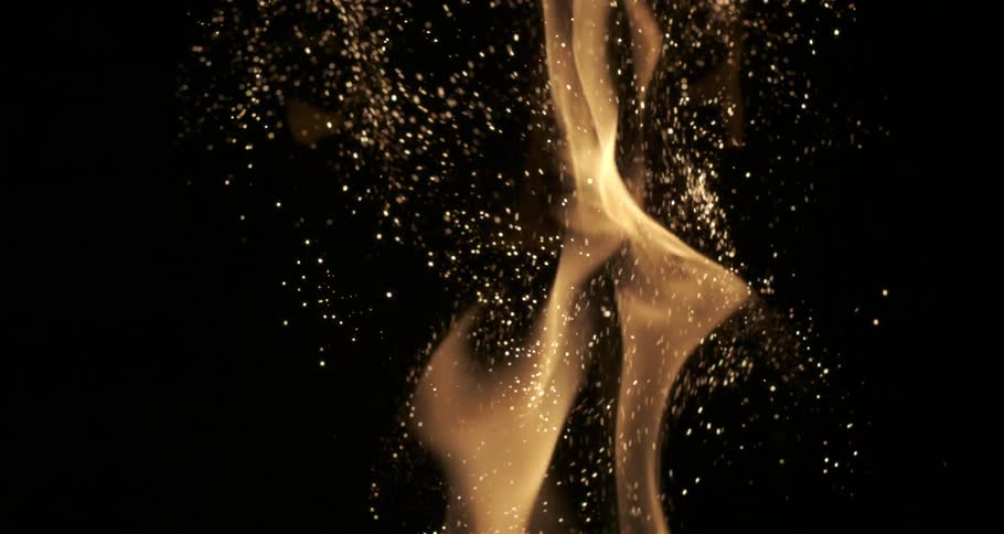 Glowing sparks and embers emerge from orange flames as they rise in the darkness