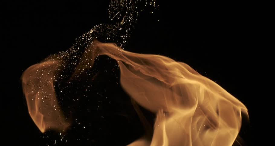 Glowing sparks and embers emerge from orange flames as they rise in the darkness