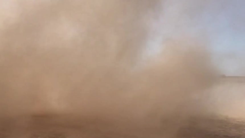 Person puts finger in front of lens while videoing dust devil in desert