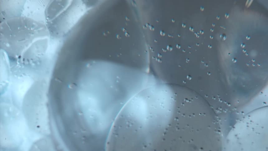 A spinning blue bubble and several particles of liquid inside