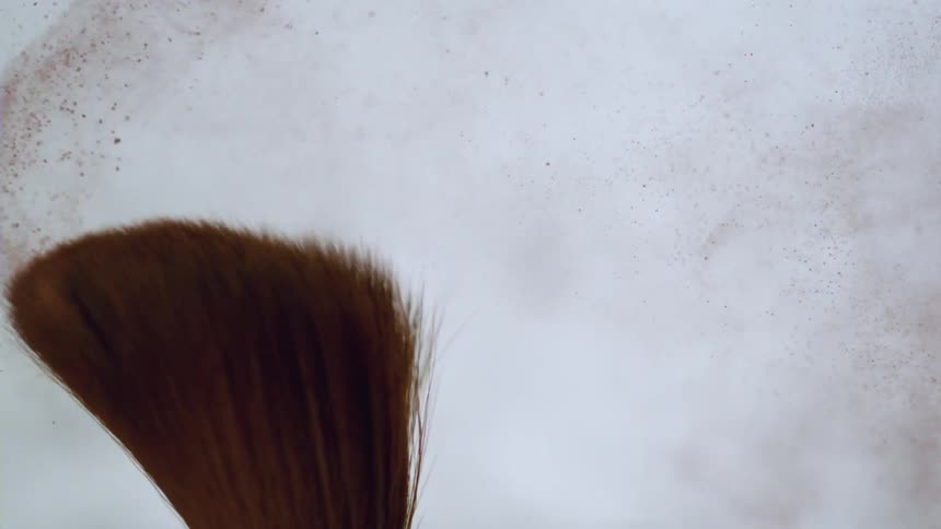 The bristles of a brush loaded with red paint being moved to the right