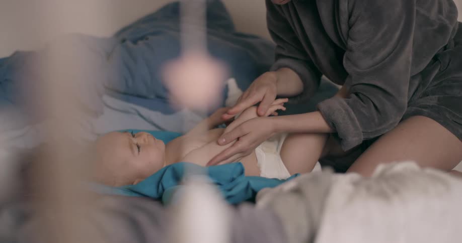 A hand caressing the belly of your baby who is lying down with his hands