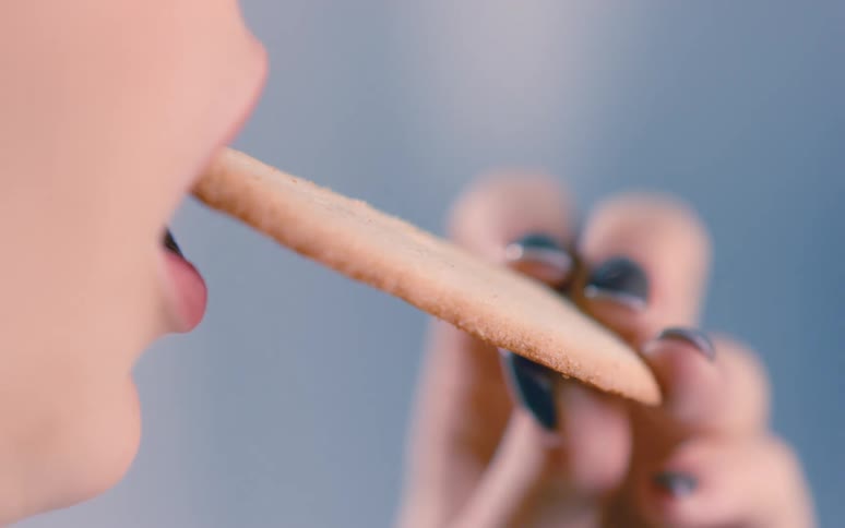 Woman takes a bite from a large cookie