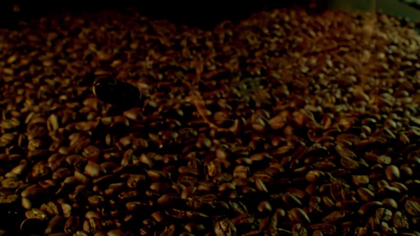 Coffee beans fall into a huge pile below with a flame over them