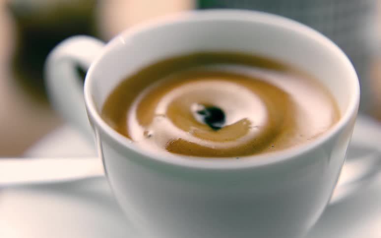 A drop of coffee falling into the cup of coffee