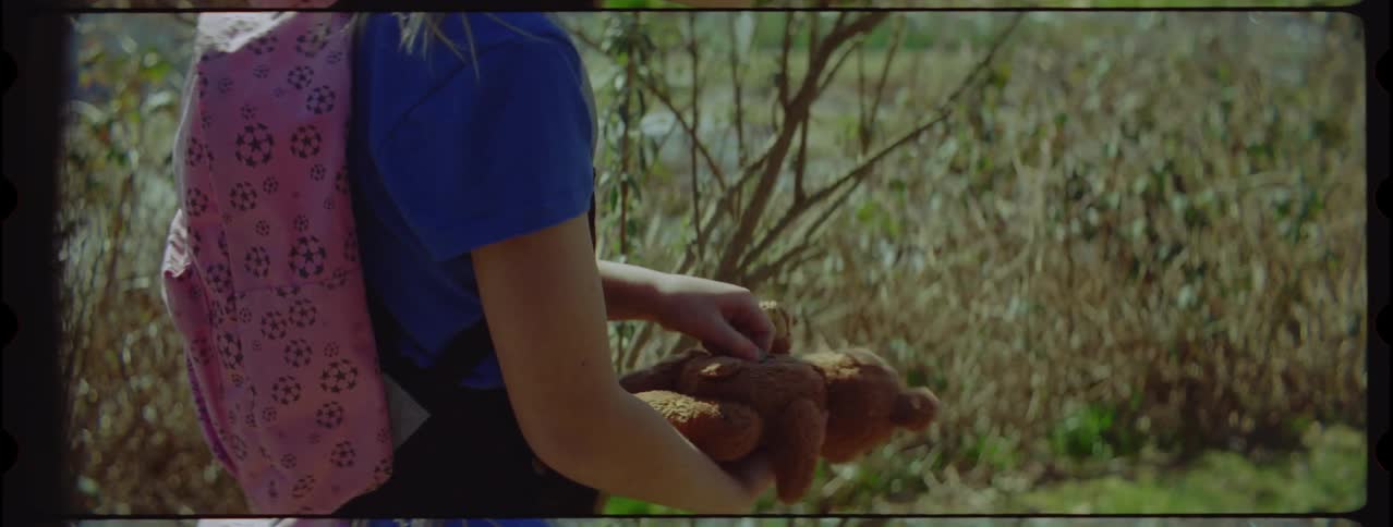 A hiking girl picks up a teddy bear