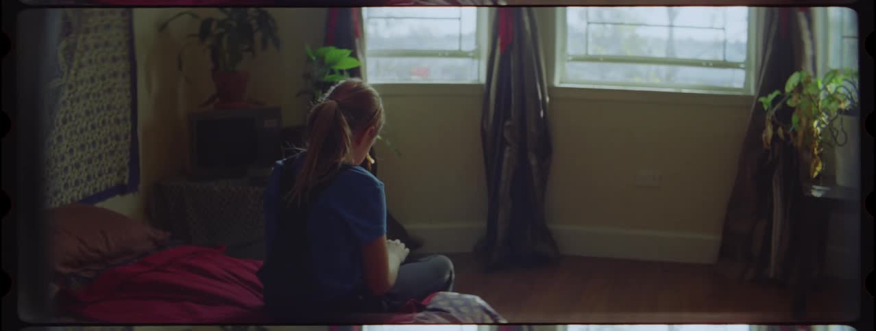 A young woman sitting on a bed holding a firearm