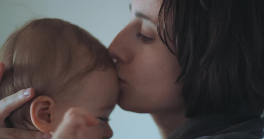 A mother kisses her baby on the forehead