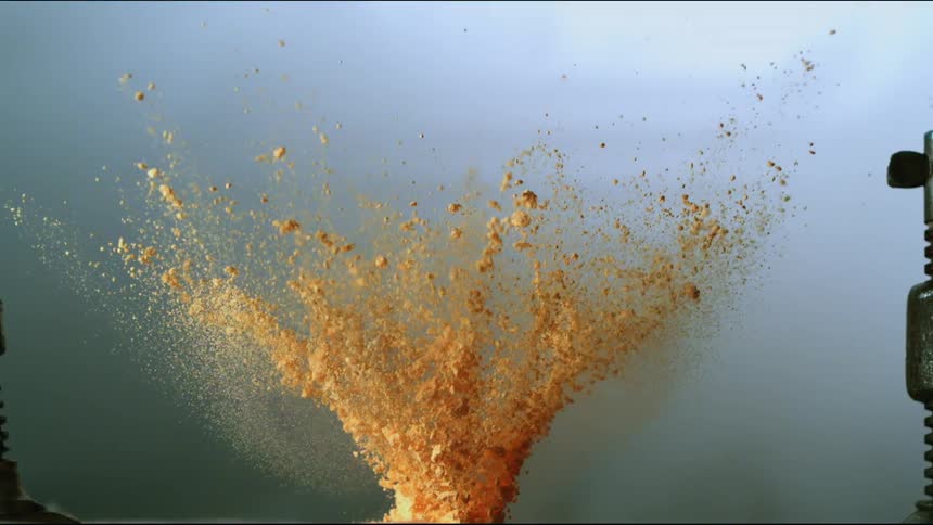 Clumps explode against murky background near metal tower