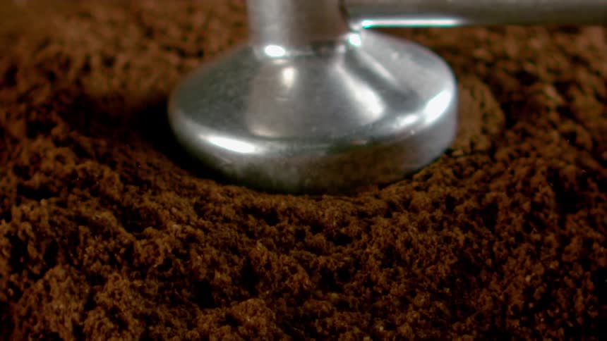 Tool being struck into ground coffee