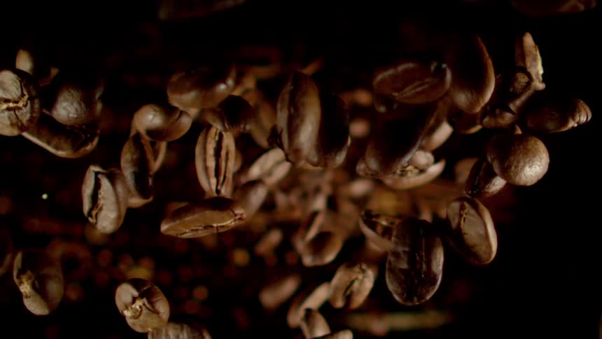 Several brown coffee beans falling