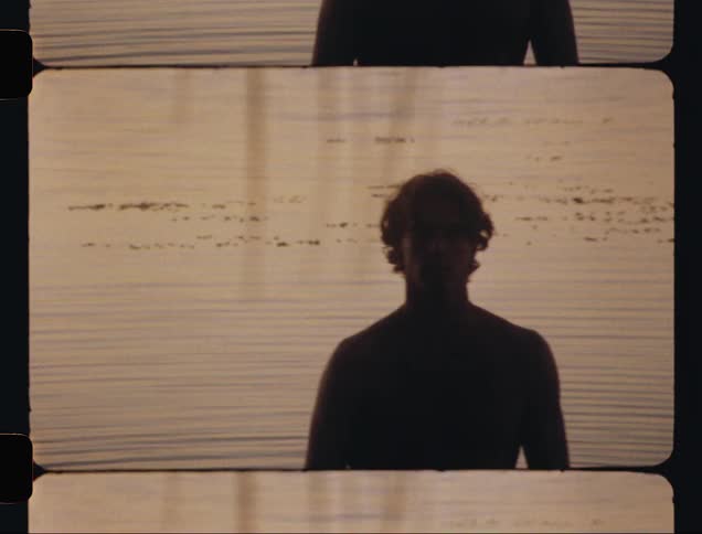 Silhouette of a young man standing in front of the ocean