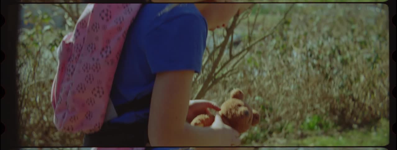 Girl finds a teddy bear on the grass near a desert