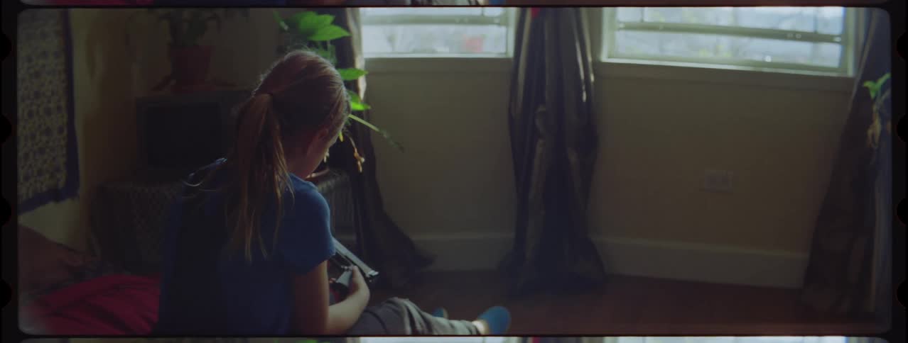 A little girl sitting on a bed holding a firearm