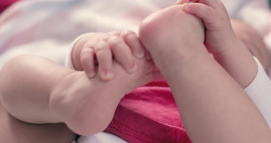 A baby with fair skin with his hands on his feet