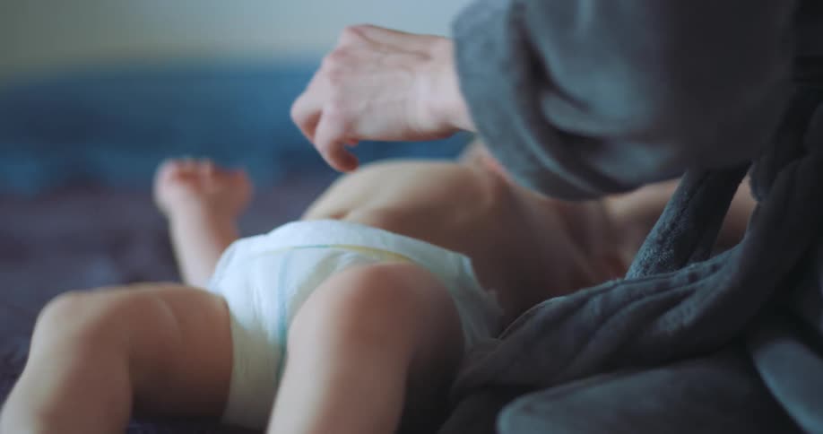 Adult hands taking care of a newborn baby wearing a diaper