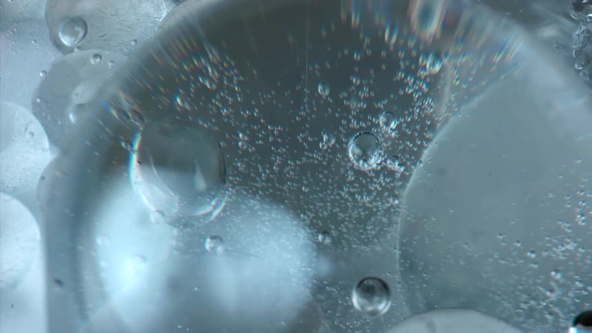 A big blue bubble and some smaller ones around it all in one liquid