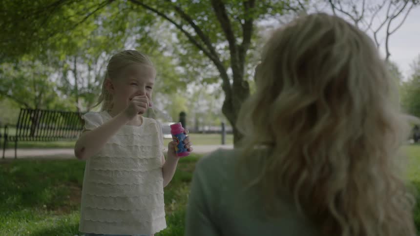 A woman watches as a child blows bubbles