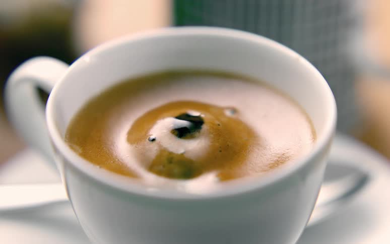 Falling drops create ripples in coffee cup