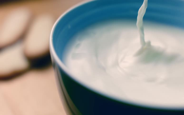Milk in a bowl flies into the air as a biscuit is dunked