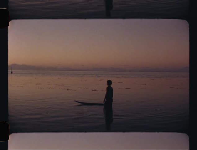 A surfer on the edge of the calm sea looking at the horizon one morning