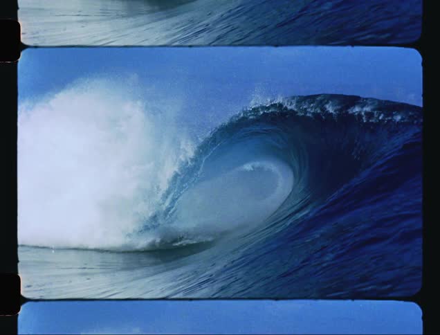 Wave collapses spraying foam under a blue sky