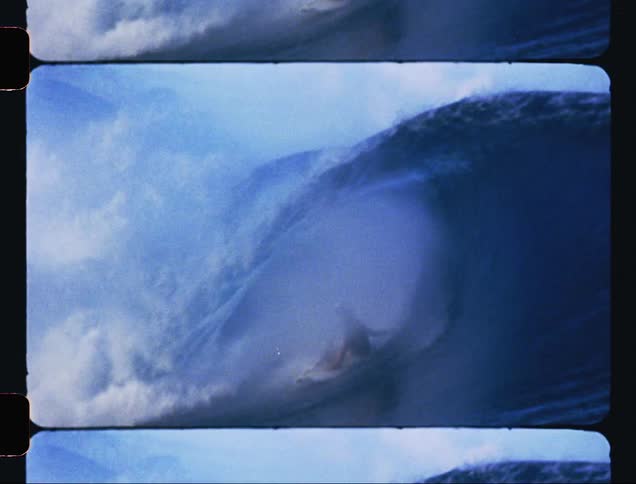 A surfer clad in a wetsuit and helmet skillfully rides the wave