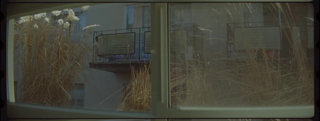 A teenage girl with a backpack sneaking into a place with grass outside the window