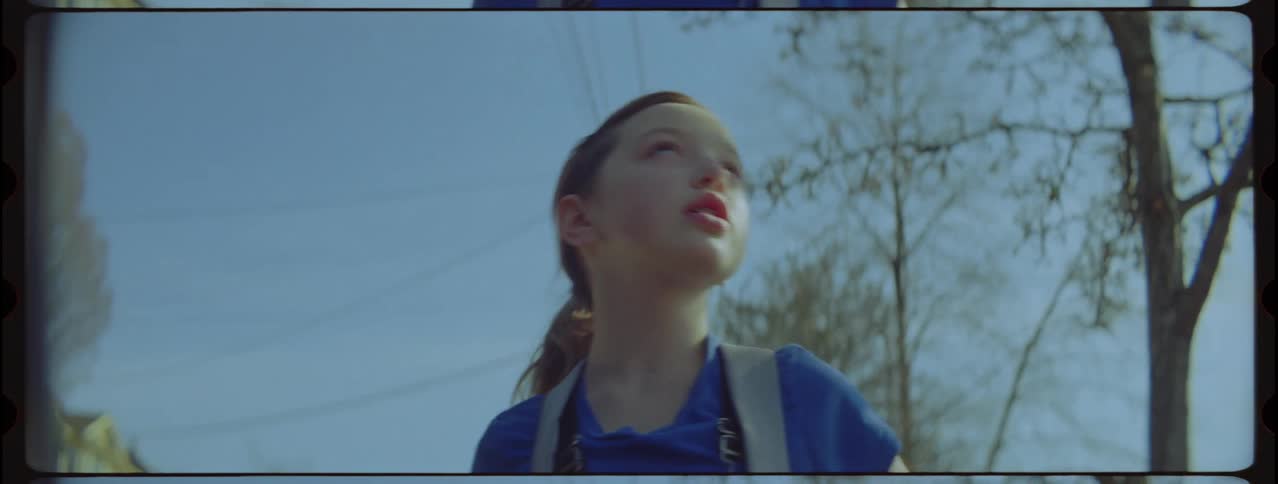 A teenage girl walking and picking something up off the ground