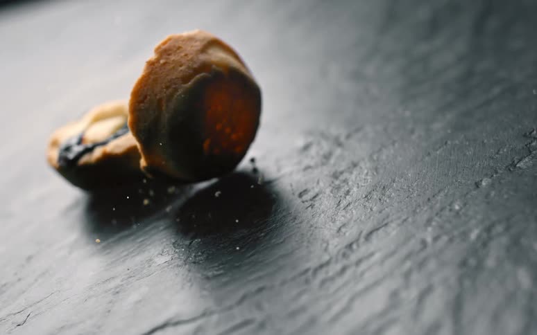 Small falling pies hit dark surface creating crumbs