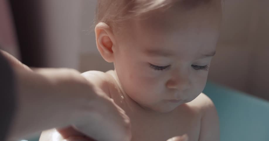 Mother baths a baby playing with a toy