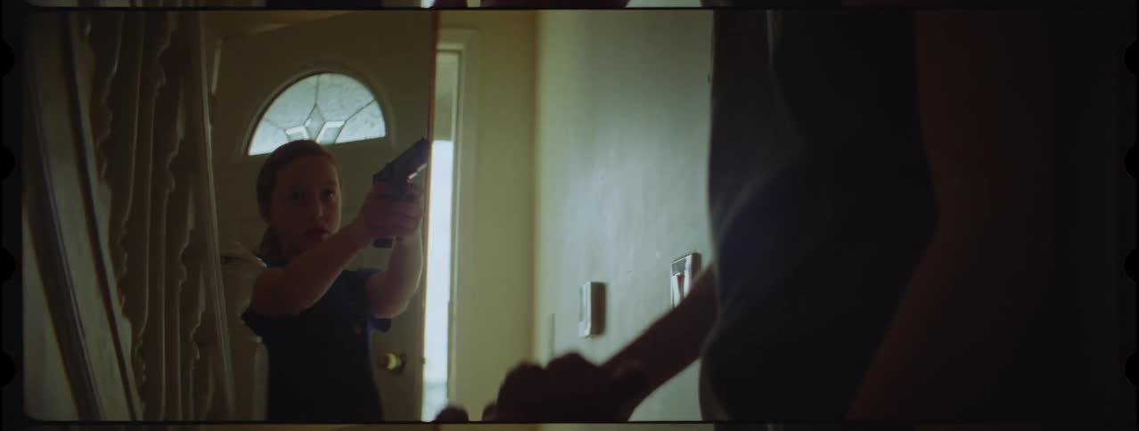 A little girl pulls a gun on an adult inside a home