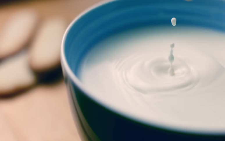 A cookie being dipped in a bowl in a blue bowl