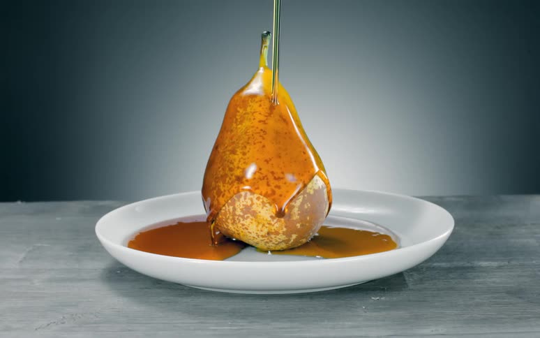 A pear is being covered in syrup