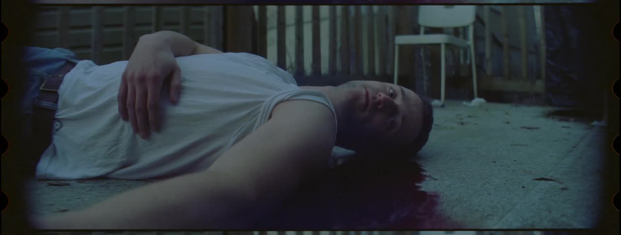 A man in a white shirt lying on the floor with his hand on his belly