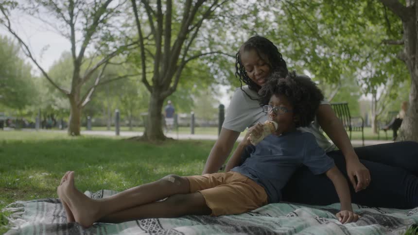 A child leans against a woman eating ice cream