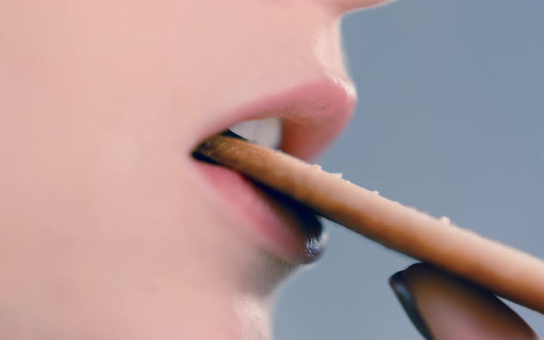 A person biting a piece of cookie with their teeth