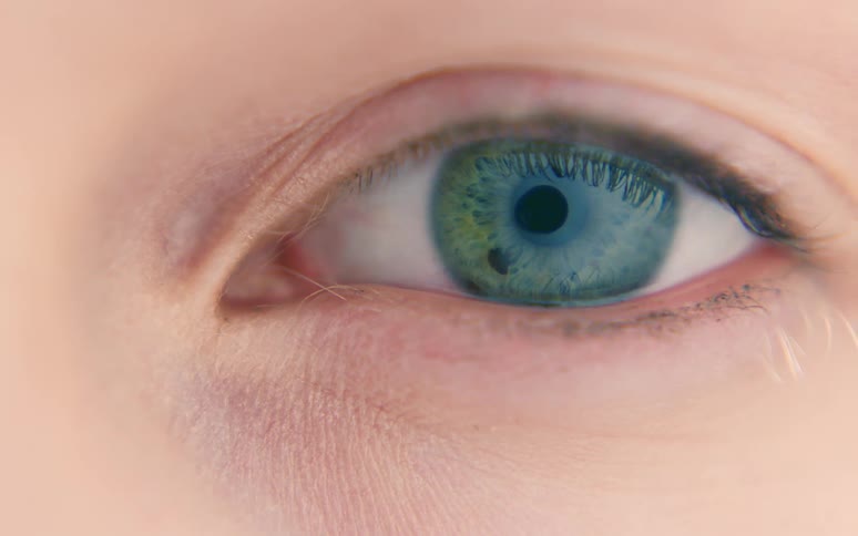 Closeup of a green eye with dilating pupil